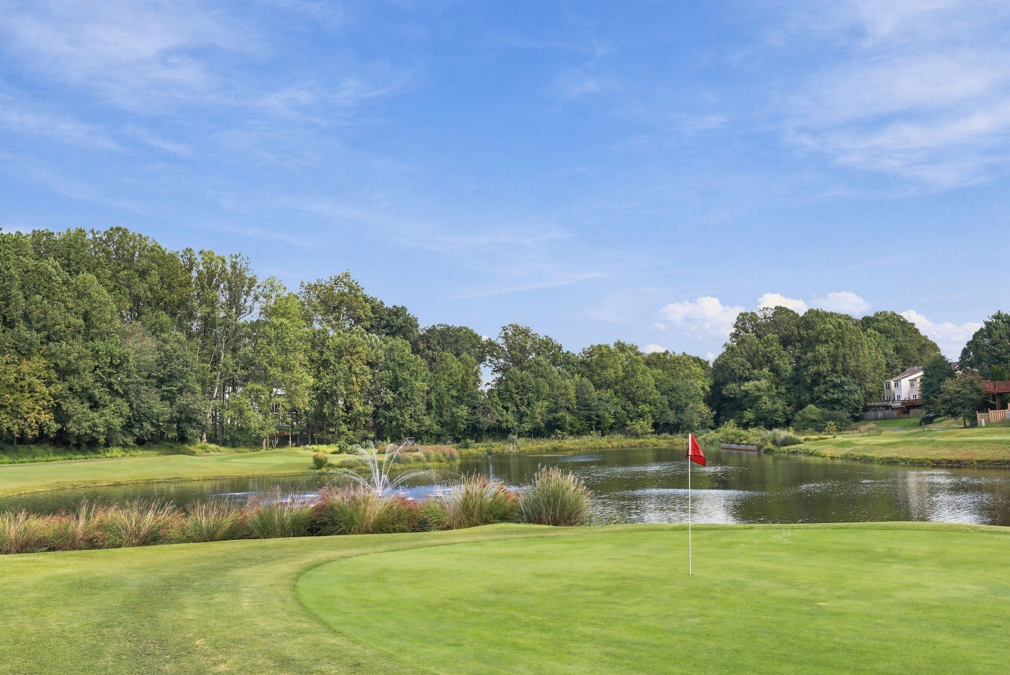 Red flag on a green beside a pond and fountain at Penderbrook Golf Club in Fairfax, Virginia